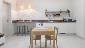 Eine moderne Küche mit Essbereich, ausgestattet mit einem Holztisch und Stühlen, einer Mikrowelle und einer kleinen Bar mit Ablagefläche darüber.