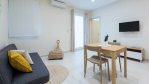 Ein modernes Wohnzimmer mit einer Couch, einem Esstisch und einem an der Wand befestigten Fernseher.