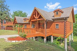 A log cabin with a porch and a small deck.