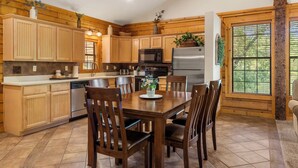 A kitchen with wooden cabinets, a dining table with chairs, and a refrigerator. - Peaceful Walk-in Cabin with Whirlpool Tub, Gas Fireplace, and Screened-in Porch (Branson)