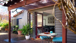 A covered patio area with a table and chairs, potted plants, and a view into the house. - Chestnut Daylesford-Log fire place, spa bath and close to all of Daylesford's attractions (Daylesford)