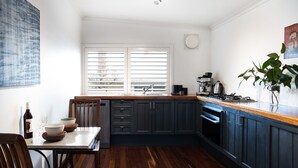A compact kitchen with dark cabinets, a wooden countertop, a gas stove, and a window with blinds. - Chestnut Daylesford-Log fire place, spa bath and close to all of Daylesford's attractions (Daylesford)