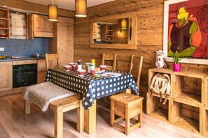 Een rustiek houten interieur met een eettafel voor vier personen, houten stoelen en een bank.