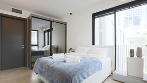 A modern bedroom with a large bed, a wardrobe, and a window with a city view. - AirTLV - Nes Tziona Luxury By The Sea (Tel Aviv)