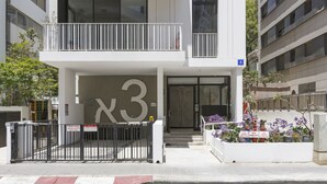 A modern building with a large '3' sign, a gated entrance, and a balcony with railings. - AirTLV - Nes Tziona Luxury By The Sea (Tel Aviv)