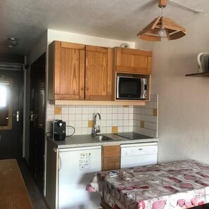 A compact kitchen with wooden cabinets, a microwave, a sink, and a refrigerator.