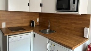 A compact kitchen with white cabinets, a microwave, a dishwasher, and a wooden countertop. - 50m from resort center, 6th floor, tv, 27m², Val Thorens (Val Thorens)