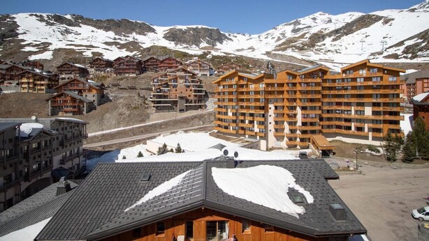A ski resort with multiple wooden buildings, including a large hotel with balconies and a ski lift visible in the background. - 50m from resort center, 6th floor, tv, 27m², Val Thorens (Val Thorens)