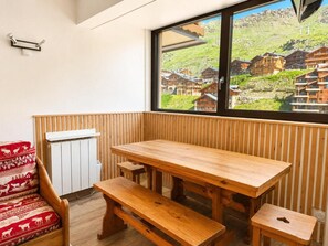 Una mesa de madera con bancos en una habitación con vistas a un pueblo a través de una ventana.