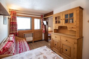 A cozy room with a bed, a wooden cabinet, and a window with curtains. - 6th floor, tv, 27m², Val Thorens (Val Thorens)