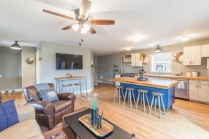 A modern kitchen with a central island, bar stools, and a ceiling fan.