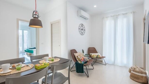 Un espace repas moderne avec une table dressée pour deux personnes, des chaises et un luminaire suspendu.