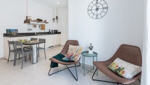 Un salon moderne comprenant un coin repas, une horloge au mur et une petite table d’appoint agrémentée d’une plante.