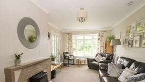 A living room with a fireplace, leather sofa, and a dining area with a table and chairs. - Roseland (Ludlow)