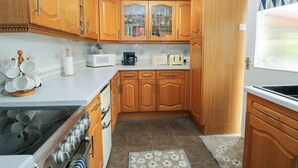 A kitchen with wooden cabinets, a microwave, a toaster, and a stove. - Roseland (Ludlow)