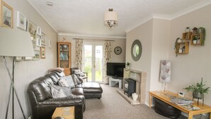 A living room with a leather sofa, a television, a fireplace, and a bookshelf. - Roseland (Ludlow)