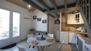 Una cuina moderna amb armaris blancs, un rentavaixelles i una zona de menjador amb una taula rodona preparada per a quatre.