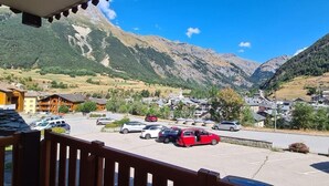 Un pueblo de montaña con edificios tradicionales, un estacionamiento y vistas de las montañas circundantes.