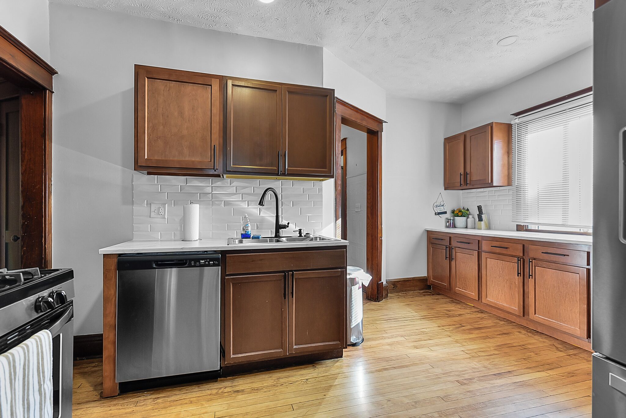 A modern kitchen with wooden cabinets, stainless steel appliances, and a white tiled backsplash.
