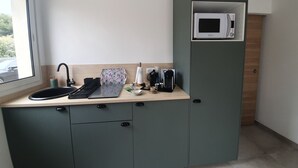 Une petite cuisine équipée d’un four à micro-ondes, d’une machine à café et d’un ordinateur portable posé sur le plan de travail.
