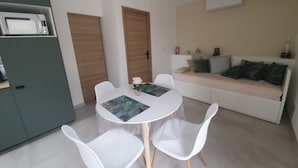 Un espace de vie compact comprenant un coin repas, une kitchenette et un canapé.