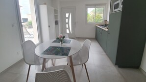 Une cuisine compacte avec un coin repas, comprenant une table ronde avec des chaises, un petit meuble et une fenêtre.