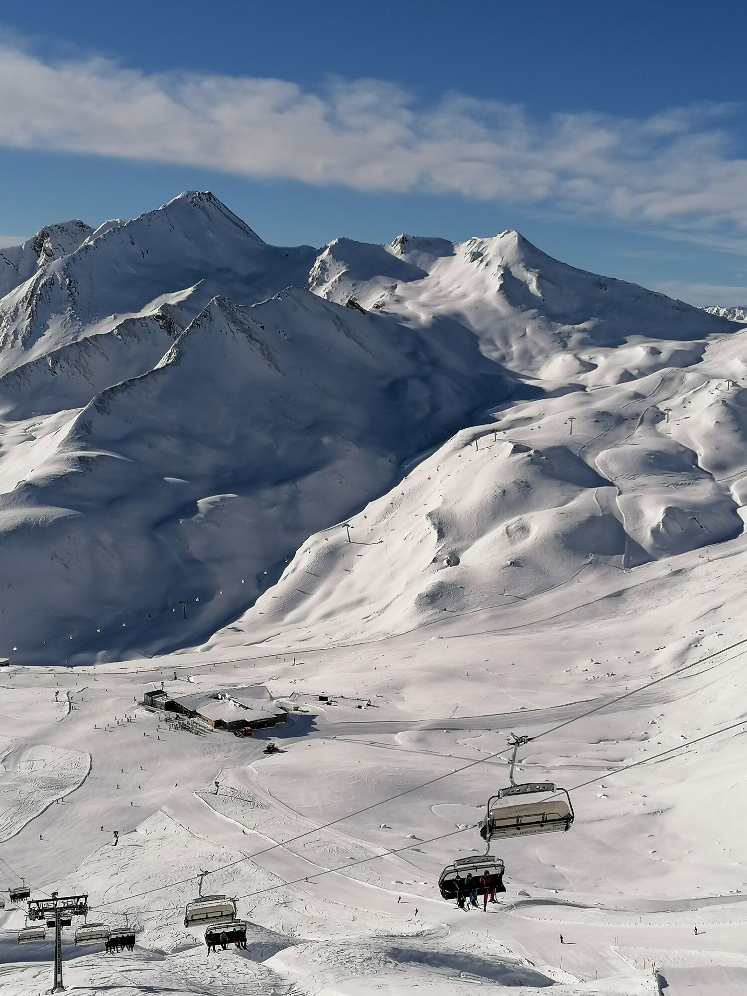Une montagne enneigée, dotée de remontées mécaniques, sous un ciel dégagé.