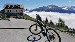 Una mountain bike parcheggiata su una strada, con vista su un edificio di un centro turistico e cime innevate sullo sfondo.