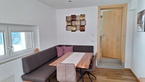 Un soggiorno moderno con un tavolo da pranzo in legno, un divano grigio scuro e una porta in legno.