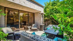 An outdoor patio with wicker furniture, a table, and a lamp.