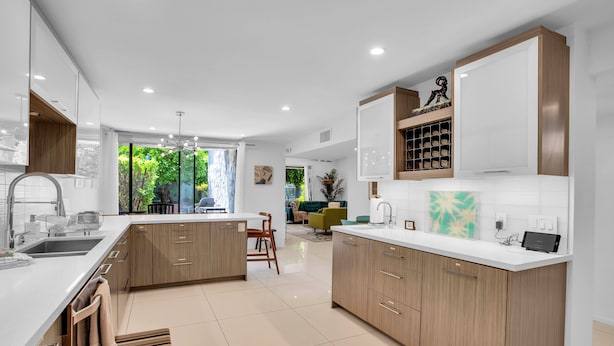 A modern kitchen with wooden cabinets, a large island, and a dining area with a sofa and chairs.
