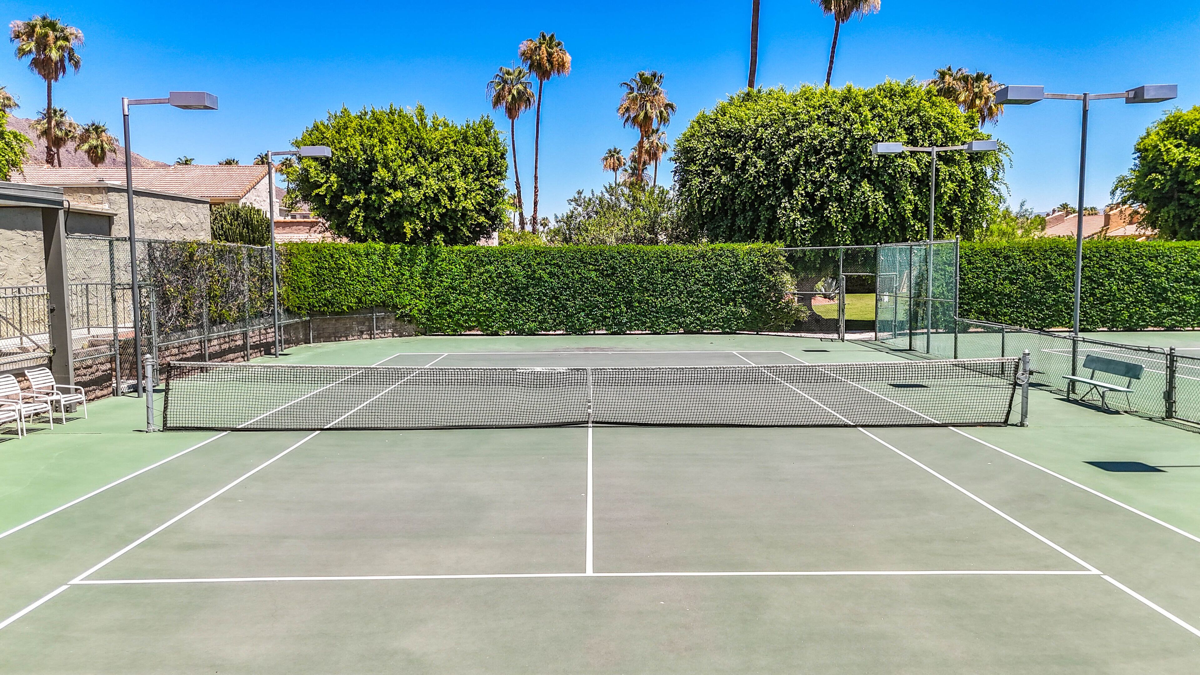 A tennis court with a net, benches, and a fence.