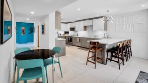 A modern kitchen with white cabinets, a central island, and bar stools.