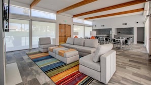 A spacious living area with a large sectional sofa, a colorful striped rug, and a wooden ceiling.