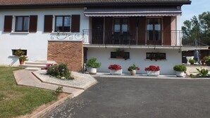 A two-story house with a balcony, potted plants, and a clear sky.
