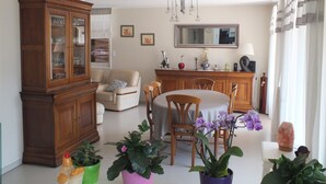 A dining area with a round table, chairs, a cabinet, and potted plants.