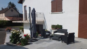 A residential building with a balcony, outdoor seating area, and potted plants.