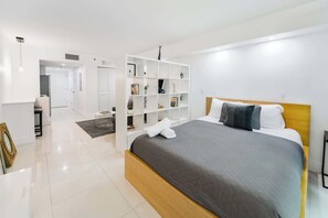 Un dormitorio moderno con una cama, un armario blanco y una estantería empotrada.