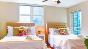 A hotel room with two beds, a ceiling fan, and large windows. - 2BR + Rooftop Pool | Free Parking Included (Miami)