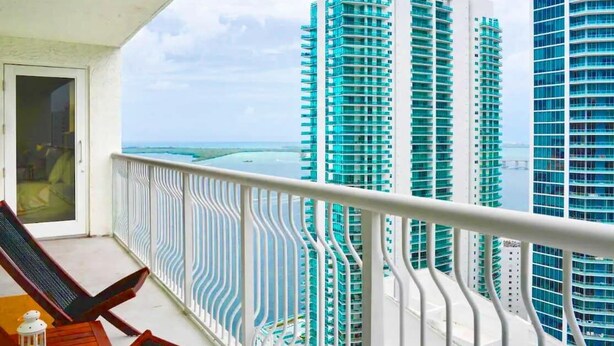 A balcony with a view of tall buildings and a beach. - 2BR + Rooftop Pool | Free Parking Included (Miami)