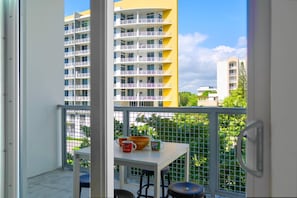 A balcony with a table, chairs, and a view of high-rise buildings.
