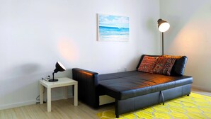 A modern living room with a black sofa, a small white table with a lamp, a yellow rug, and a painting of a seascape on the wall. - Free Parking - Near to Wynwood & Design District (Miami)