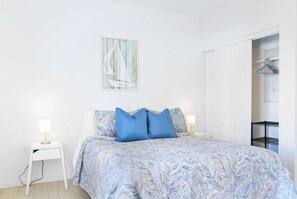 A bedroom with a bed, two bedside tables, a wall-mounted artwork, and a wardrobe.