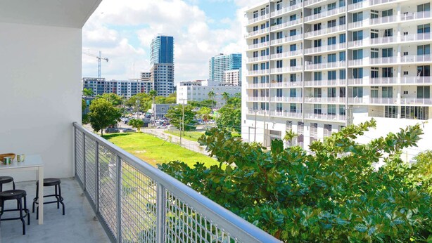 A balcony with a view of a cityscape, including modern buildings and a grassy area. - Free Parking - Near to Wynwood & Design District (Miami)