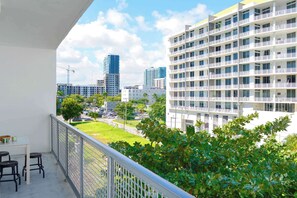 Ein Balkon mit Blick auf eine Stadtlandschaft, darunter moderne Gebäude und eine Grünfläche.