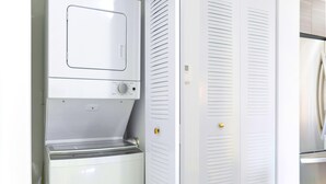 A compact kitchen with a built-in washer and dryer, a white refrigerator, and a double door closet with a golden handle. - Free Parking - Near to Wynwood & Design District (Miami)