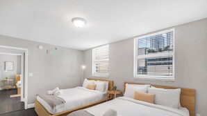 Hotellihuone, jossa on kaksi sänkyä, pieni pyöreä pöytä ja ikkuna, jossa on sälekaihtimet.