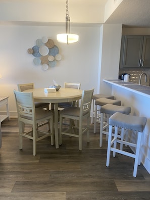 Uma área de refeições com uma mesa redonda, seis cadeiras e um lustre.