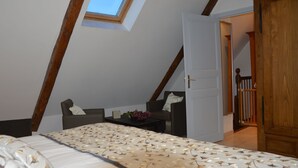 Une chambre avec un puits de lumière, un lit recouvert d’une couvre-lit à motifs, une petite table avec un vase et une chaise.