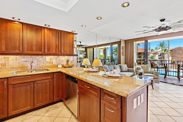 A modern kitchen with wooden cabinets, a granite countertop, and a built-in dishwasher. - Hawaiian-inspired studio with ocean view (Lahaina)